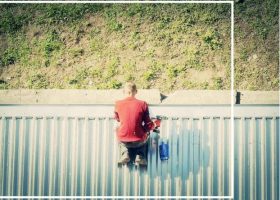 A man is sitting on top of a metal roof.