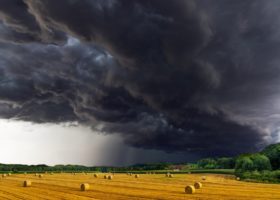 A field with hay bales under storm clouds, captured by an experienced photographer.