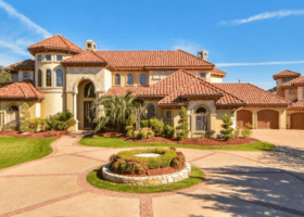 A beautiful home with a large driveway and an eye-catching roof color.