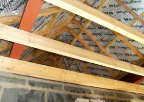 The roof of a house is being built with wooden beams.