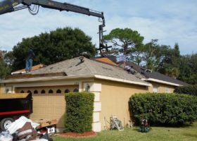 A crane is being used for roof replacement on a house.