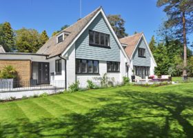 A house with a lawn and trees in the background - important for a new homeowner to know about the roof.