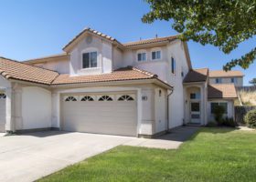 A home with two garages and a grassy yard that is protected from stuff that endangers the roof.