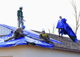 A professional roofing inspection of a blue tarp on a roof.