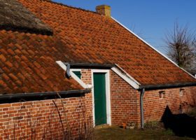 A brick house with a thatched roof facing roof problems.