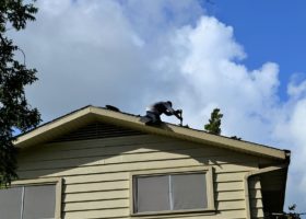 A local roofing contractor is standing on the roof of a house.