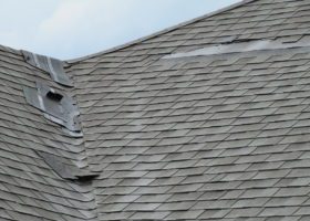 A shingled roof with a hole in it, attracting storm chasers.