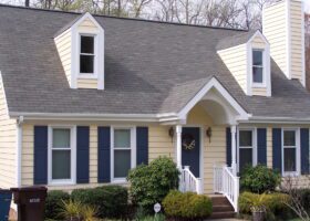 A yellow house with blue shutters and sidings.