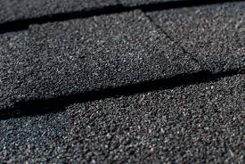 A close up of a black shingled roof with shingle roofing.