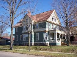 A house with a distinguished copper roofing, located on the corner of a street.