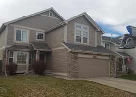 A house with mold and algae growing on its exterior walls and a garage in front of it.