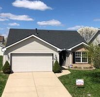 A suburban home with a garage and driveway suitable for retrofitting roofing.