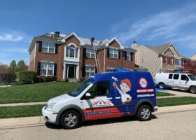 A van is parked in front of a house. The homeowners are considering hiring a roofing contractor to inspect and repair the roof.