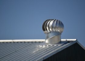 A metal chimney on top of a metal roof with metal roofing.