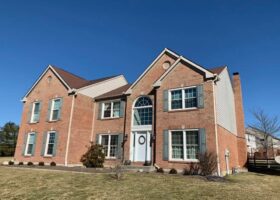 A brick home with a large front yard, perfect for installing a new roof.