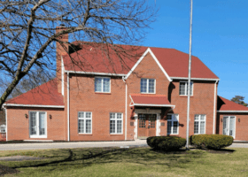 A red brick house with a flag in front of it, perfect for a roofing contractor.