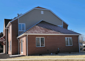 A brick house with a blue sky and questions to ask about the roof.